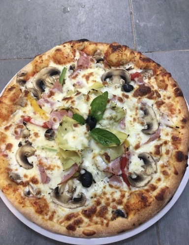 Une assiette contenant un belle pizza 4 saisons de votre restaurant Bella Casa Nemours